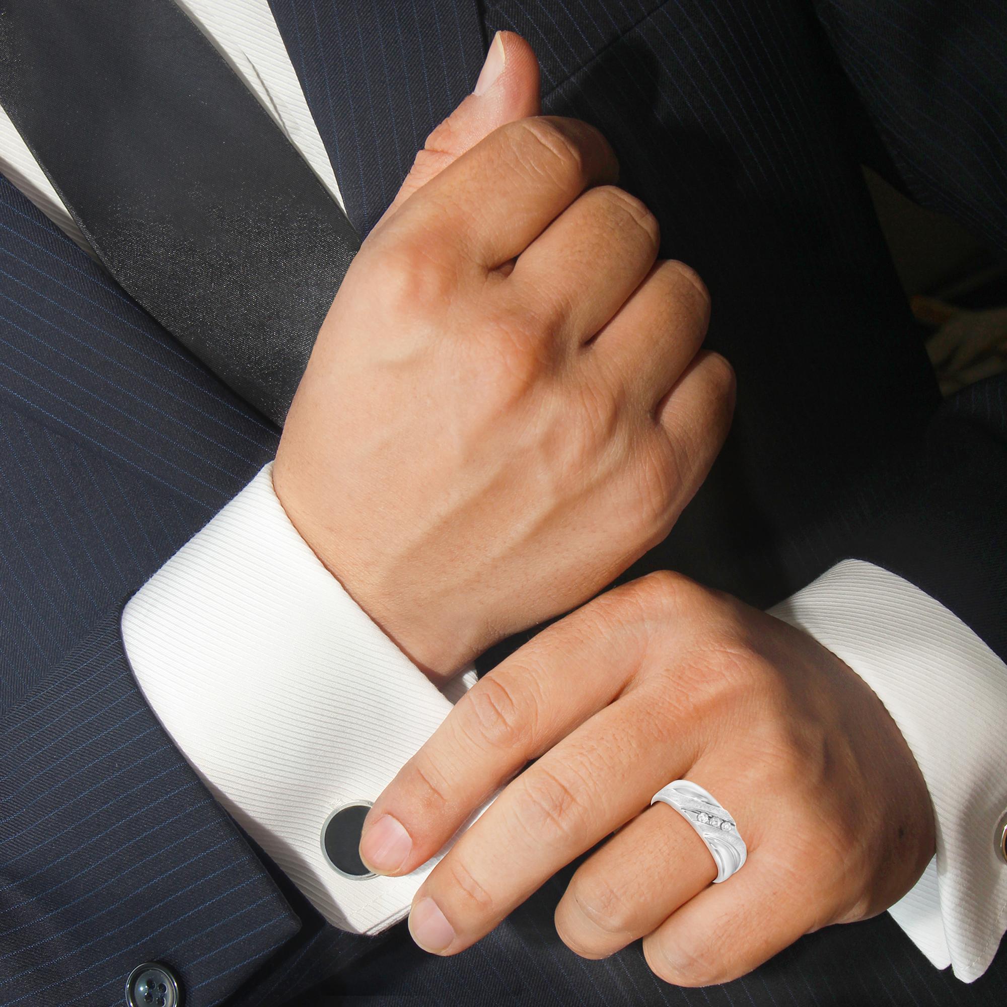 Hands adjusting cufflink on pinstripe suit; silver ring and black tie visible.