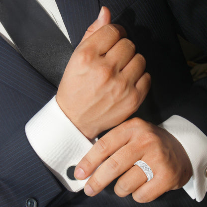 Hands adjusting cufflink on pinstripe suit; silver ring and black tie visible.
