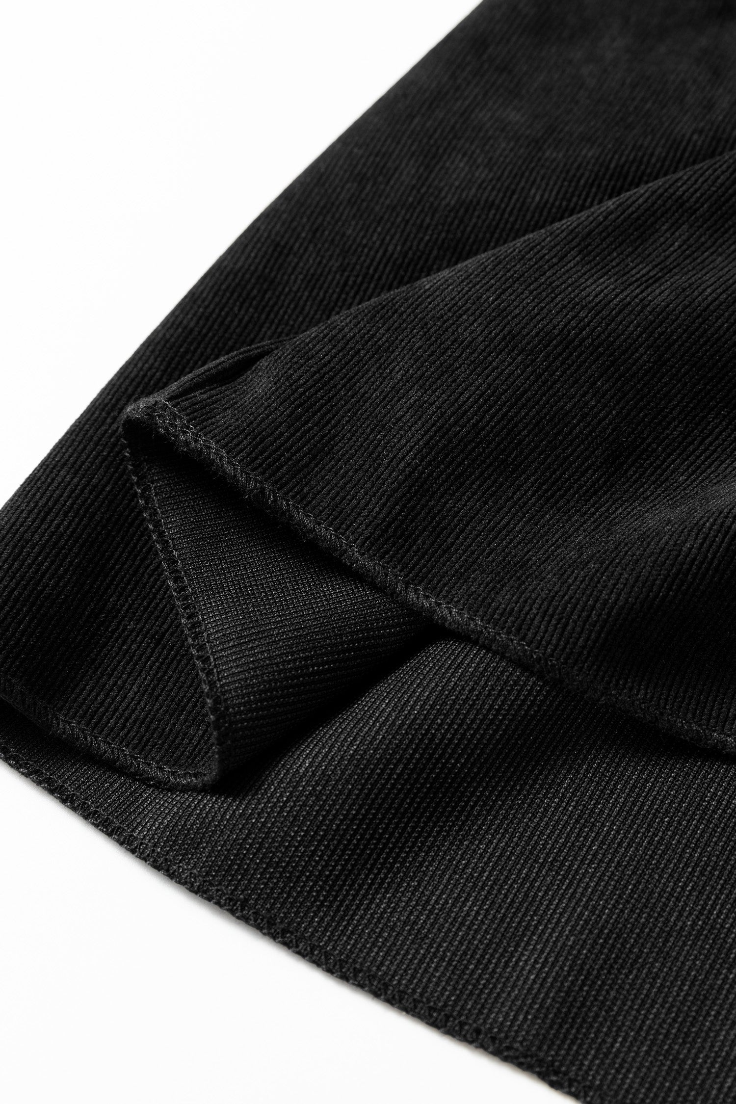 Close-up of black ribbed fabric folded on a white background.