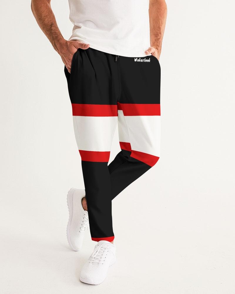 Man wearing black joggers with red and white horizontal stripes, white sneakers, and a white shirt.
