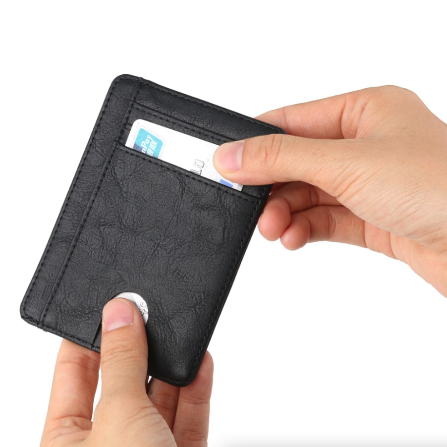Hands holding a black leather card holder, inserting a card into a front pocket, white background.