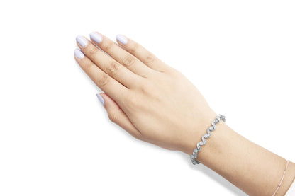 Hand with light purple nails wearing a silver twisted bracelet on a white background.