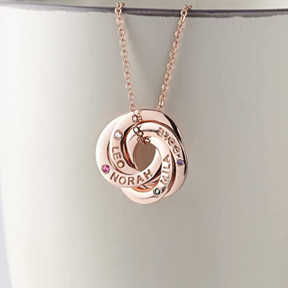 Rose gold necklace with three interlocking rings engraved with names and inset with small gems.