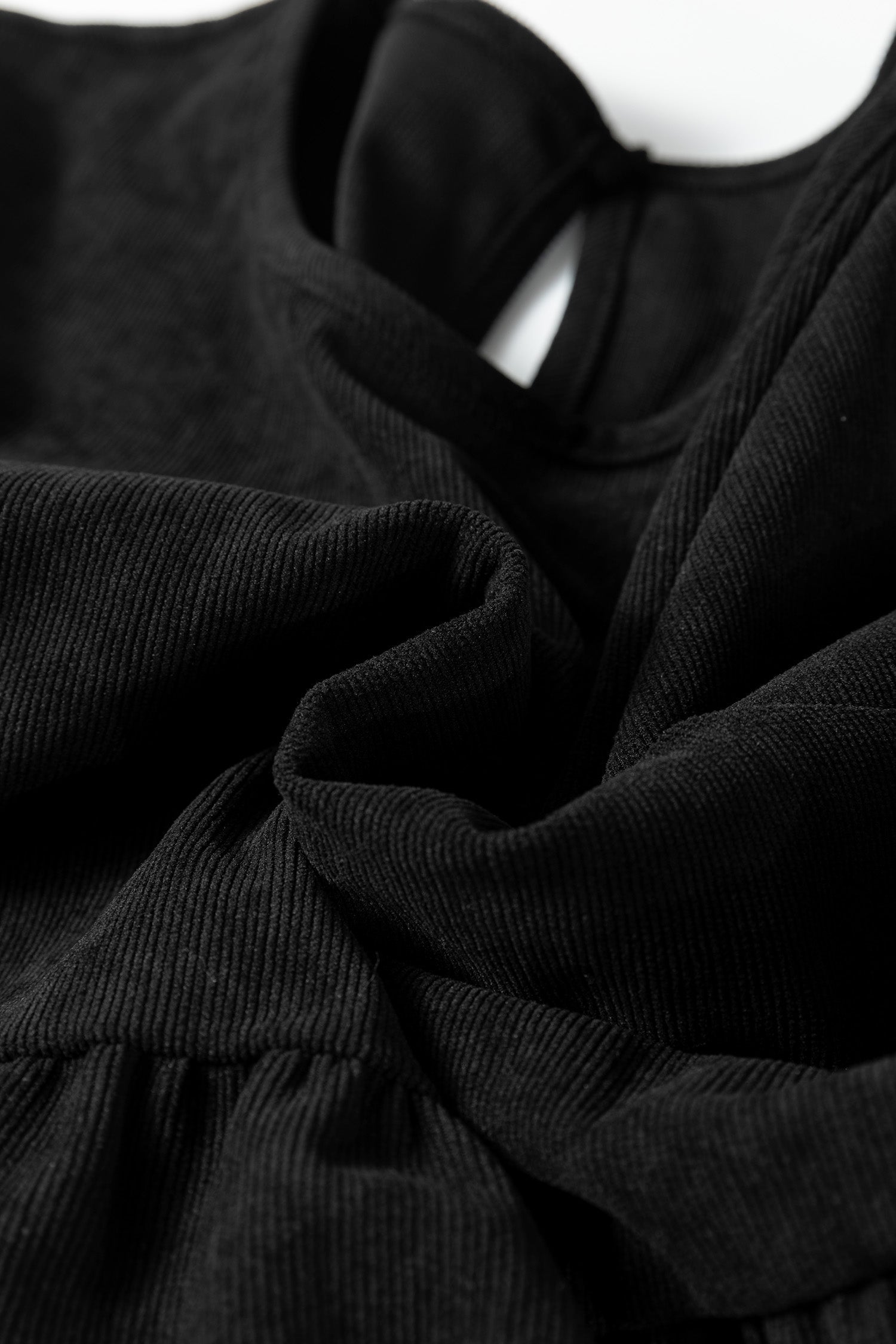 Close-up of black ribbed fabric with gathered folds and soft texture.