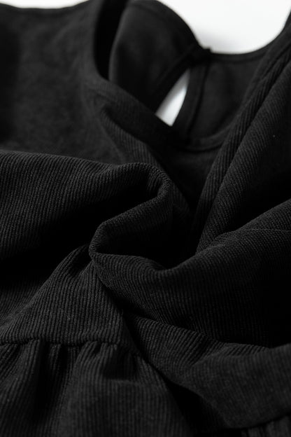 Close-up of black ribbed fabric with gathered folds and soft texture.