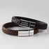 Two leather bracelets: one black, one brown, with engraved silver clasps on a gray background.