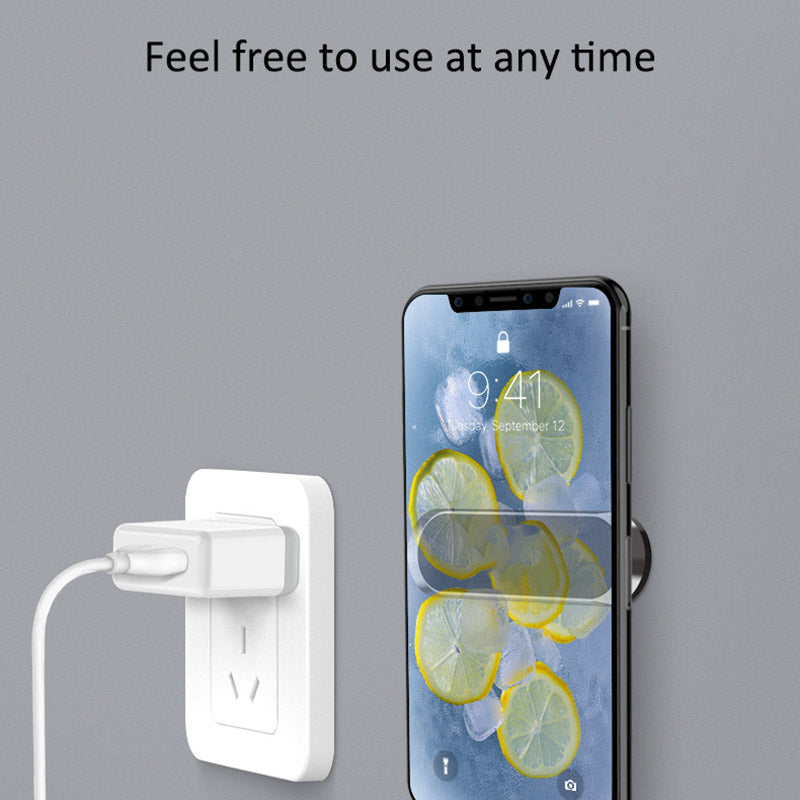 Smartphone with lemon wallpaper charging on wall mount near a white power outlet.