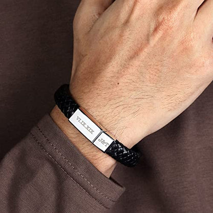 Hand with brown sleeve wearing a black braided bracelet featuring a metallic clasp with engravings.