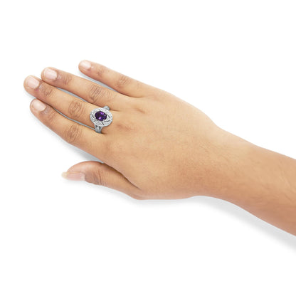 Hand wearing a silver ring with a large purple gemstone, on a white background.
