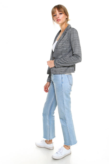 Woman in a plaid jacket, light blue jeans, and white sneakers against a plain white background.