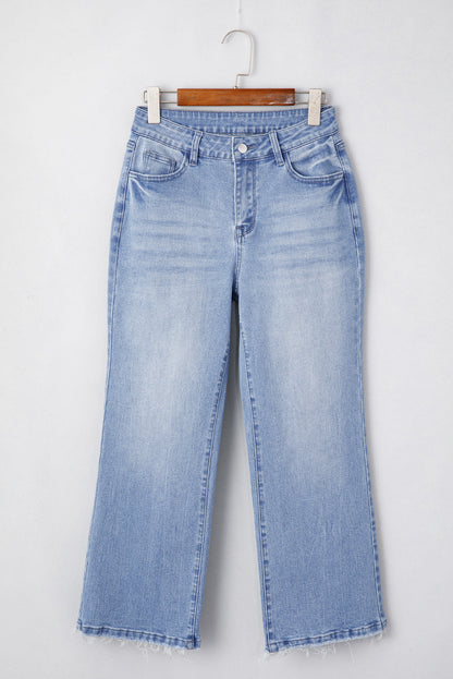 Light blue flared jeans with a frayed hem, hanging on a wooden hanger.