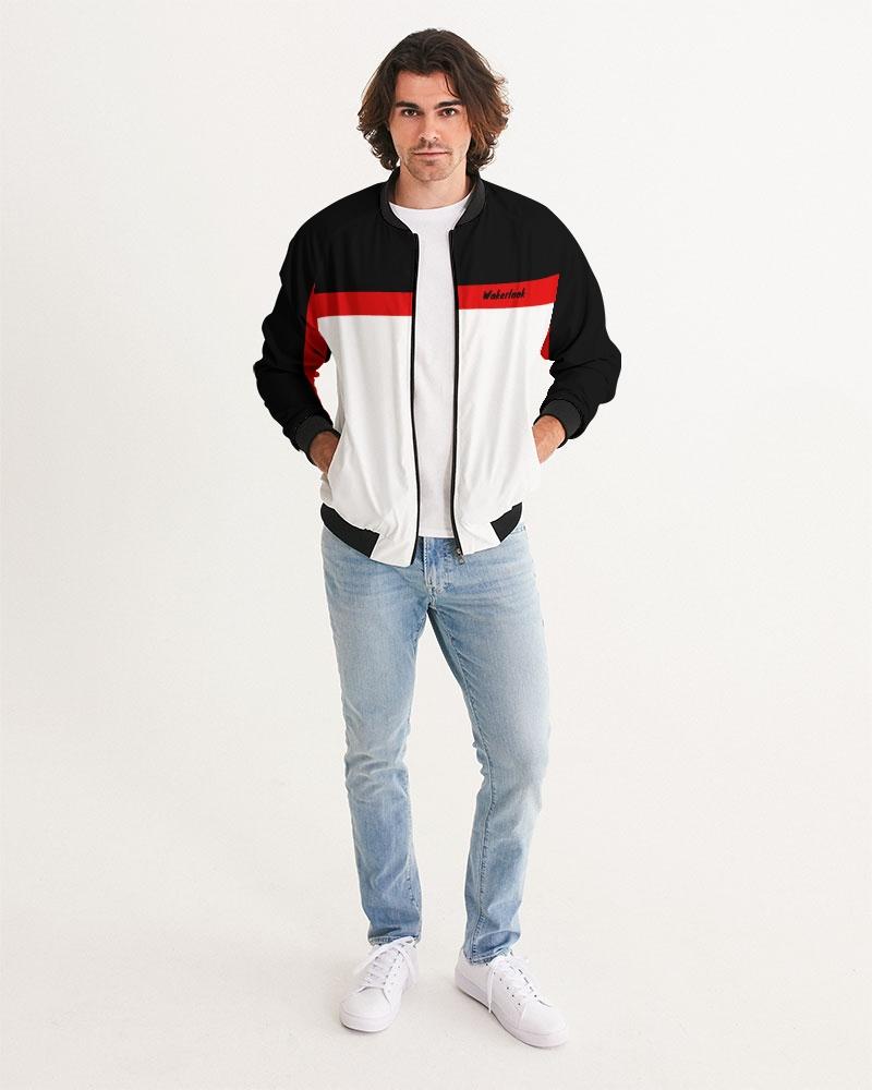 Man in a black, red, and white jacket, light jeans, and white sneakers standing on a white background.