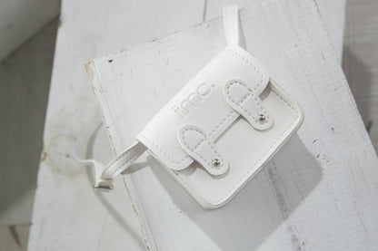 Small white leather bag with a strap on a wooden surface. Two buckles and logo on the flap.