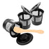 Three black reusable coffee filters with lids, and a beige plastic spoon on a white background.