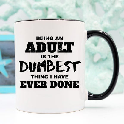 White mug with black handle, text reads: "Being an adult is the dumbest thing I have ever done."