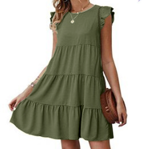 Woman in a green sleeveless ruffled dress, holding a round woven bag, wearing jewelry.