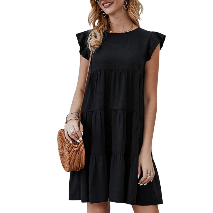 Woman in a black tiered dress with ruffle sleeves, carrying a round woven bag.
