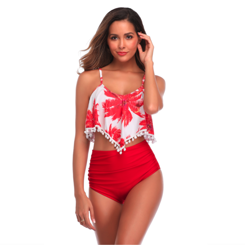Woman in a red floral bikini top with pom-poms and red high-waisted bottom, smiling and posing.