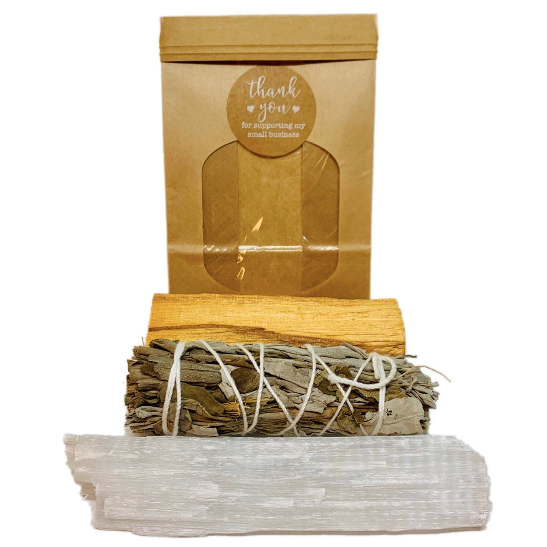 Brown package with a "thank you" sticker, white crystal, sage bundle, and palo santo wood.