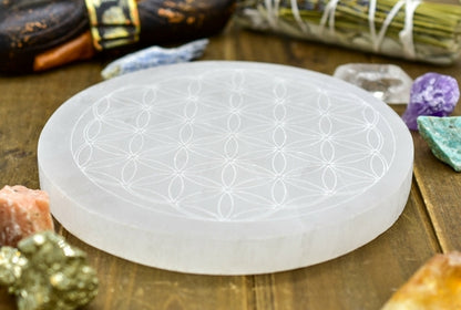 Clear round crystal with geometric pattern surrounded by assorted colorful gemstones on wood.