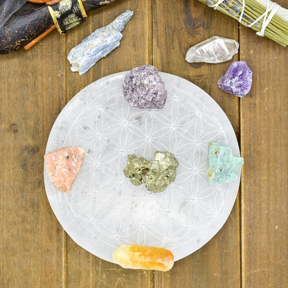 Crystals on a patterned white stone plate with a wooden background; various colors and shapes.