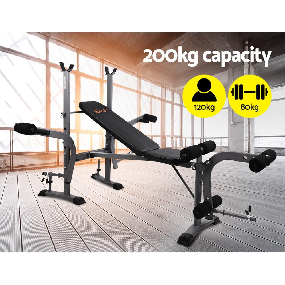 Black workout bench with weights, 200kg capacity, yellow capacity icons, wooden floor, large windows.