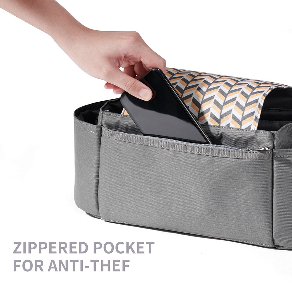Hand placing phone in gray zippered pocket with black, white, and mustard chevron lining.