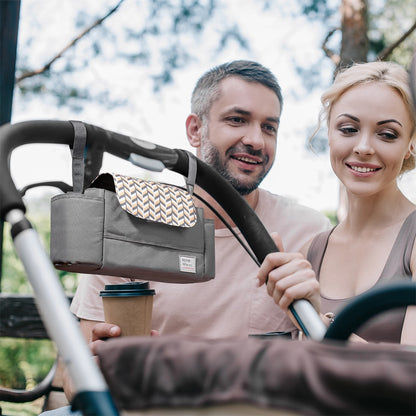 Couple with stroller; gray organizer, patterned flap; man holds a coffee cup; tree background.