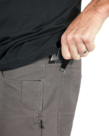 Hand placing a black object in gray pants pocket; person wearing a black shirt, with a silver ring.