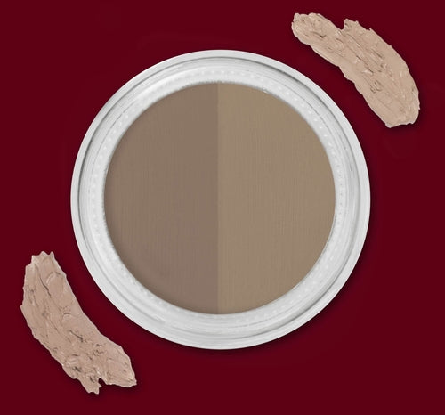 Round makeup compact with two beige shades on a burgundy background, cream smudges nearby.
