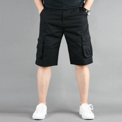 Person wearing black cargo shorts and white sneakers against a gray background.