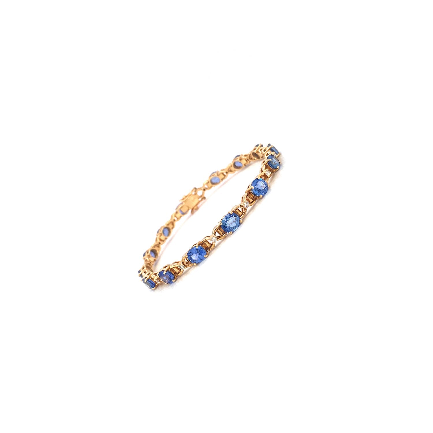Gold bracelet with blue gemstones in a linked pattern on a white background.