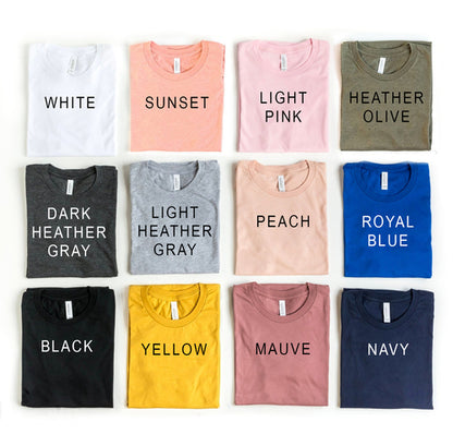 Twelve folded t-shirts in various colors with labels: white, sunset, pink, olive, gray, peach, blue, black, yellow, mauve, navy.