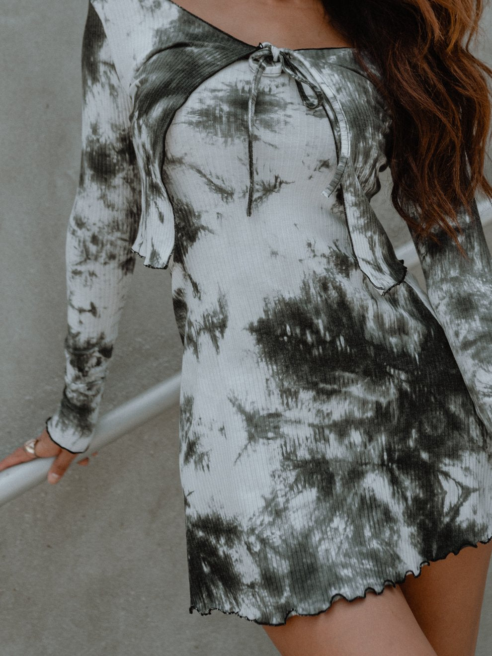 Woman in a black and white tie-dye dress with long sleeves and a bow at the neckline.