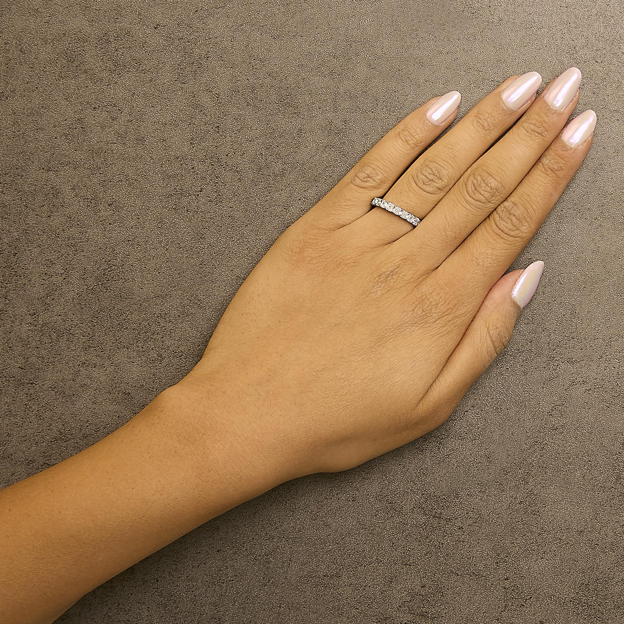 Hand with light pink polished nails and diamond ring on a textured brown surface.
