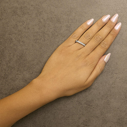 Hand with light pink polished nails and diamond ring on a textured brown surface.