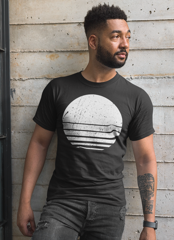Man in a black shirt with white abstract circle design, standing against a textured concrete wall.