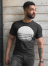 Man in a black shirt with white abstract circle design, standing against a textured concrete wall.