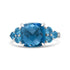 Silver ring with a large, faceted blue gemstone, flanked by smaller round blue stones.
