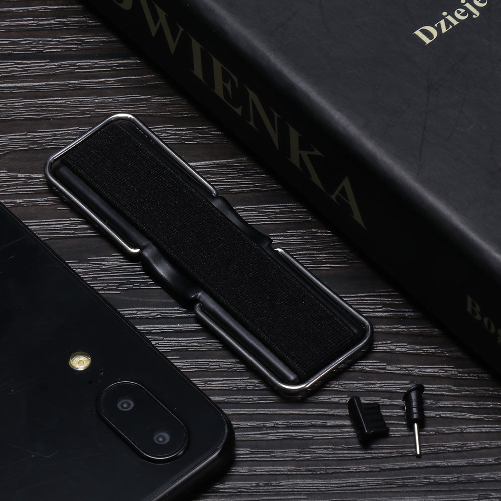 Black phone, book, and small accessories on a dark wooden table.