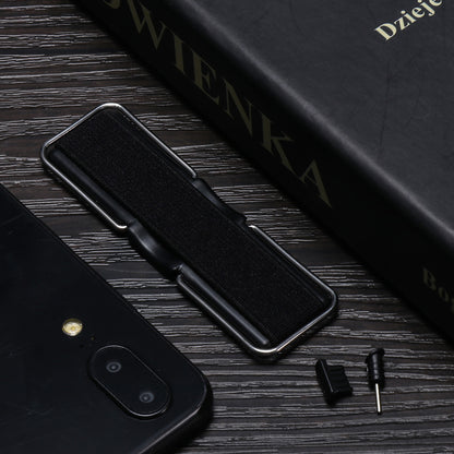 Black phone, book, and small accessories on a dark wooden table.