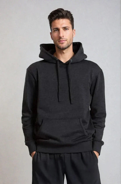 Man wearing a dark hoodie and pants, hands in pockets, against a light gray background.