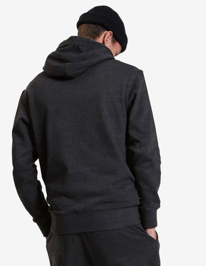 Man in dark hoodie and beanie, facing away with hands in pockets, against white background.