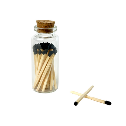 Jar of wooden matches with black tips, topped with cork; two matches crossed beside it.