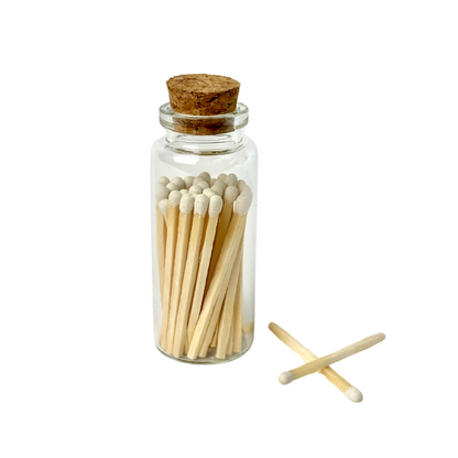 Glass jar with cork lid filled with wooden matches, two matches crossed outside on white background.