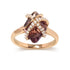 Gold ring with a central dark pink stone wrapped in diamond-studded bands.