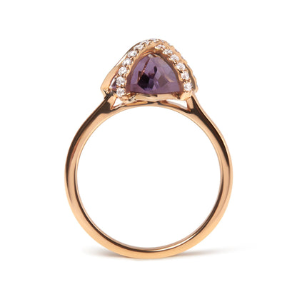 Gold ring with purple triangular stone and surrounded by small white gems.