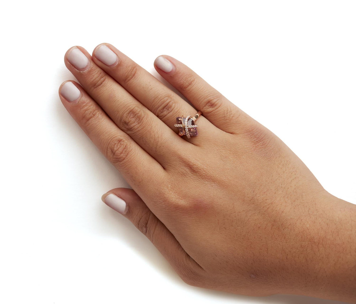 Hand with pale pink nails, wearing a gold ring with gemstones on a white background.