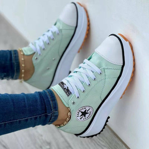 Mint green sneakers with white toe caps, star logo, and orange-brown soles, worn with jeans.