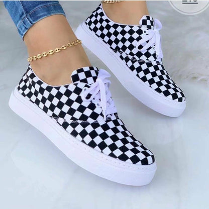 Black and white checkered sneakers with white laces and soles, worn with a gold anklet.